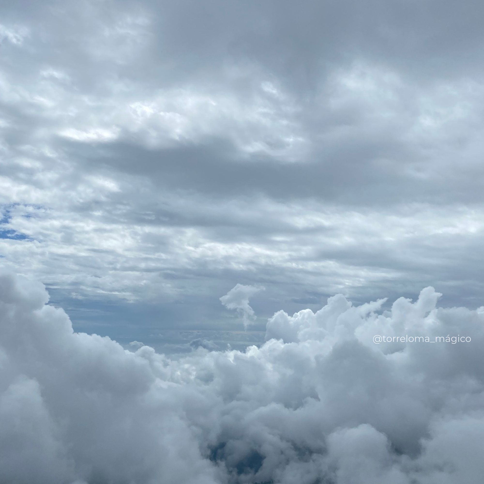 Espectacular mar de nubes blancas y densas sobre las montañas bajo un cielo dramático y encapotado.
